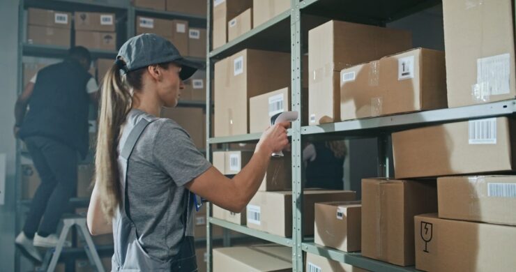 Warehouse worker scanning boxed products for inventory management in a growing wholesale distribution environment