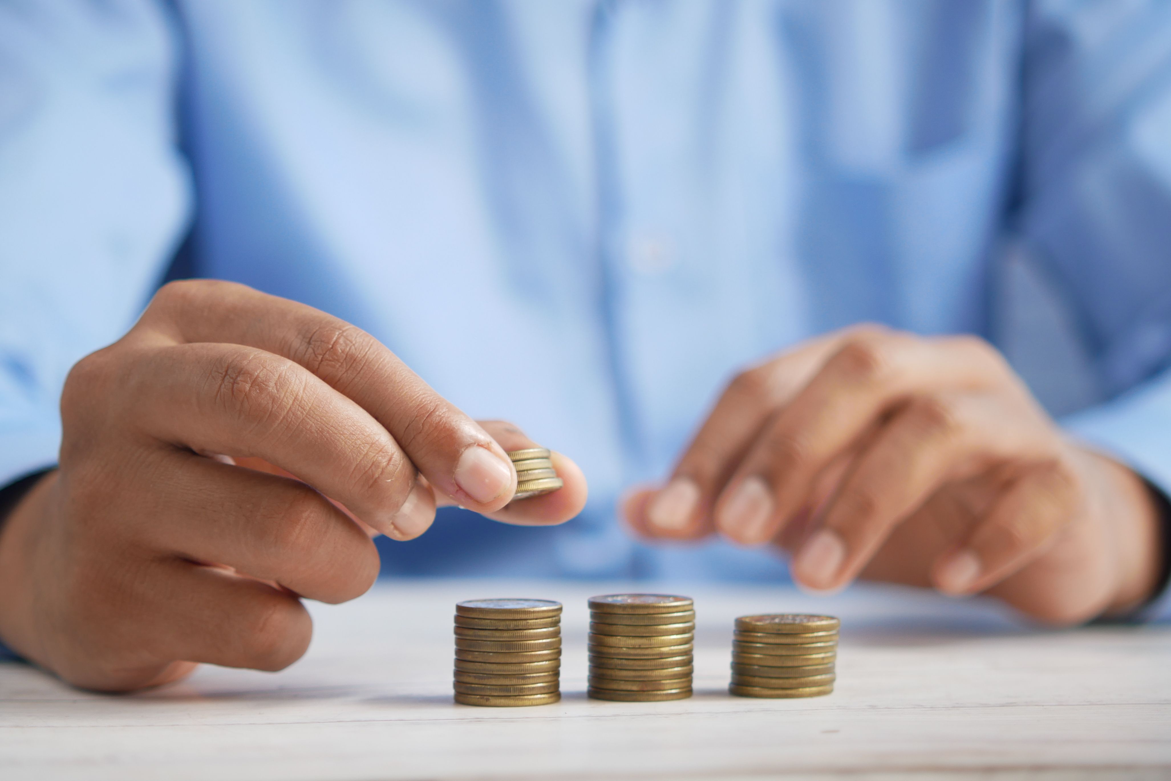 Hands stacking gold coins symbolizing business cost savings